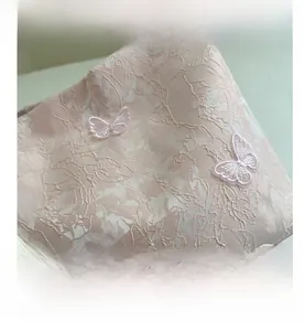 Close-up of pink jacquard fabric with embroidered 3D butterfly and white tassels on a tote bag