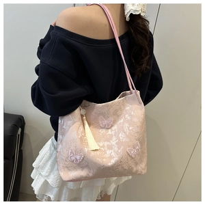 Detail of pink lace tote bag featuring 3D butterfly embroidery and white bead tassel