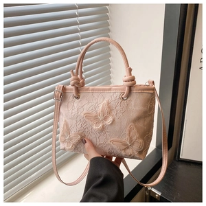 Dettaglio della borsa in pizzo rosa con delicati ricami a farfalla 3D e texture fine