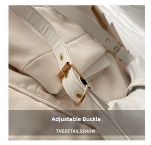 Détail de la bandoulière réglable en cuir crème avec boucle dorée et œillets dorés