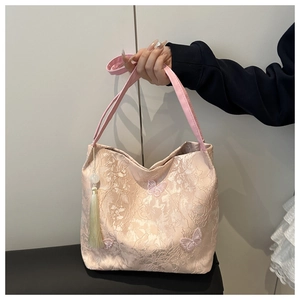 Close-up of pink jacquard tote bag with butterfly embroidery and green tassel detail