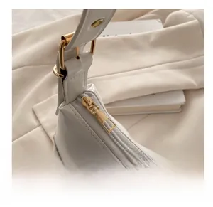Vue détaillée de la fermeture éclair dorée et du cuir verni blanc nacré du sac à rivets