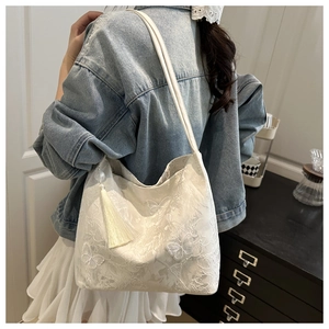 Close-up of white lace tote bag featuring intricate floral and butterfly embroidery details
