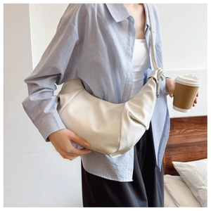 Detail of cream white pleated dumpling bag with side knotted shoulder strap design