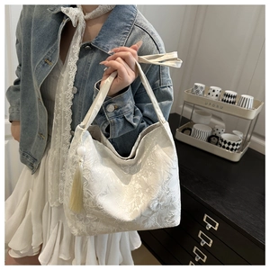 Detail of white lace embroidery tote bag with decorative pearl fringe tassel charm