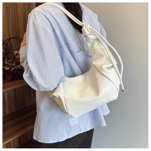 Close-up of white pleated PU leather dumpling bag with decorative knotted shoulder strap