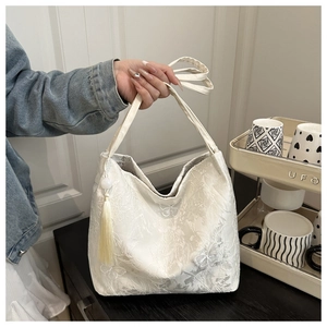 Close-up of cream white lace tote bag featuring elegant butterfly embroidery and silk tassel