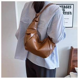 Detail of brown hobo tote bag featuring side pleats and stylish knotted shoulder strap