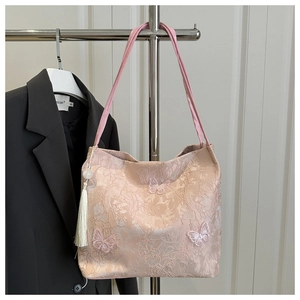 Detail of pink floral tote bag featuring 3D butterfly embroidery and white tassel charms