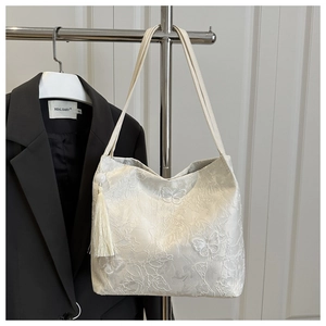 Detailed shot of white floral lace embroidery and tassel on the large tote bag