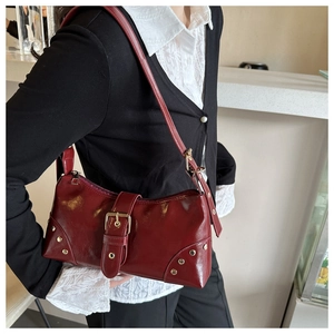 Dettaglio della borsa a spalla rosso vino vintage con rivetti dorati e fibbia decorata