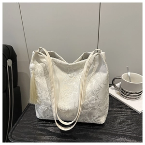 Detailed close-up of white lace tote bag with butterfly embroidery and tassel charm