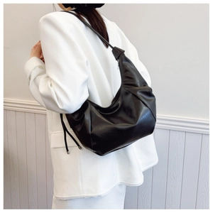 Detail view of the black soft leather hobo bag showing the knot decoration and pleats