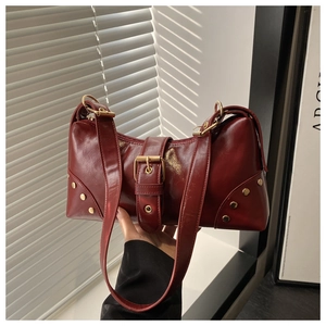 Detail of dark red glossy leather tote with gold rivets and vintage buckle decoration