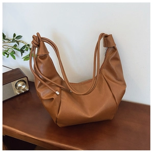 Close-up of caramel brown hobo bag featuring a knotted shoulder strap and pleated texture