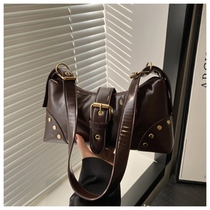 Detail of dark brown leather shoulder bag with gold buckles and rivet accents