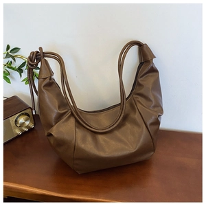 Close-up of retro brown pleated croissant bag with knotted strap on wooden desk