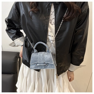 Mini light blue denim handbag with silver chain strap worn by a model in casual attire
