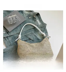 Detail of hand-woven straw tote bag featuring white cylindrical handles with knot accents