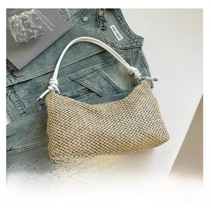Detail of woven straw tote with white shoulder strap, silver hardware and decorative knots