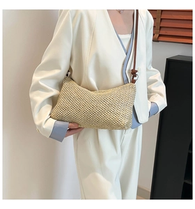 Close-up of beige handwoven tote bag with brown leather straps and metal ring detail
