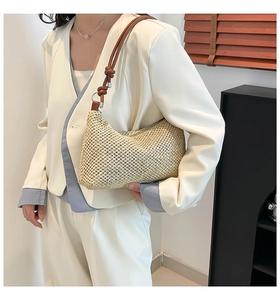 Detail of woven straw tote bag with brown leather shoulder strap and knot design