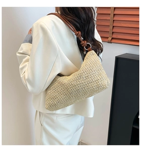 Detail of hand-woven straw tote with leather shoulder strap and silver metal rings
