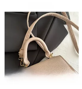 Close-up of beige lychee grain leather handbag with top handle and golden hardware detail