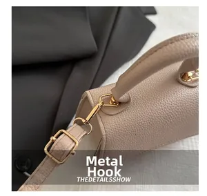 Detailed close-up of beige lychee grain leather with shiny gold metal hardware hooks