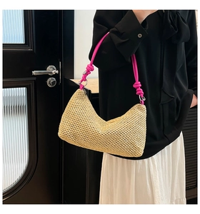 Detail of beige straw woven shoulder bag with vibrant pink knotted rope handle