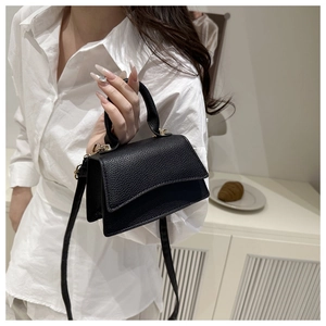 Close-up of black litchi pattern leather mini bag with elegant gold metal hardware