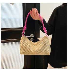 Detail of hand-woven straw tote featuring bright pink knotted shoulder straps and metal rings