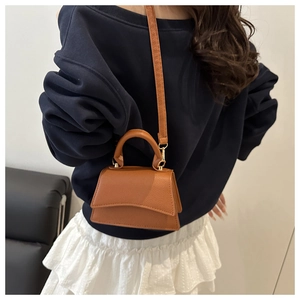 Detailed view of brown litchi pattern leather satchel with elegant gold-tone hardware