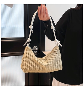 Detail of hand-woven straw tote with white rope shoulder strap and metal hardware