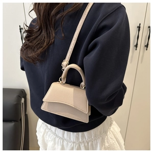 Detailed view of beige mini crossbody bag in lychee pattern faux leather with gold hardware