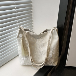 Elegant white lace tote bag with butterfly embroidery and tassel on a sunny windowsill