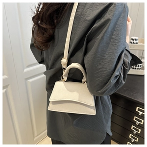Detail of white lychee leather mini square handbag with curved flap and top handle