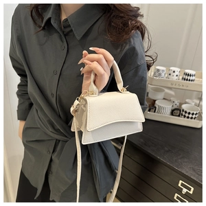 Detail of cream-colored crossbody bag featuring lychee grain texture and gold hardware