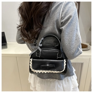 Détail du sac à bandoulière en cuir noir avec bordure en dentelle et ruban à carreaux