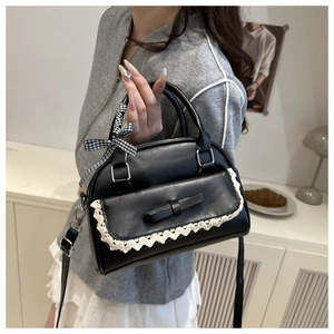 Détail du sac à main noir en similicuir avec dentelle blanche et nœud décoratif