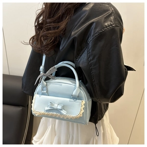 Détails d'un sac bandoulière bleu clair avec dentelle et nœud porté par un mannequin