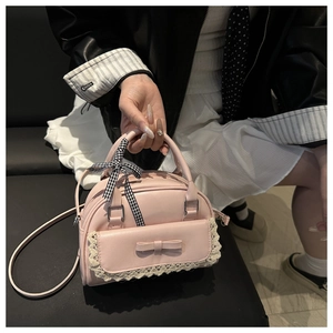 Détail du sac à main rose avec bordure en dentelle, nœud et ruban à carreaux