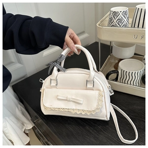 Détail du sac à main crème avec nœud en cuir, dentelle et ruban à carreaux noir