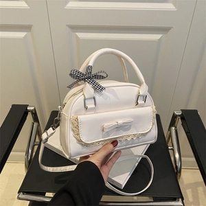 Sac bandoulière minimaliste en similicuir blanc avec dentelle et nœud sur une chaise