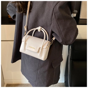 Close-up of a cream-colored mini square bag showing the long shoulder strap and top handle