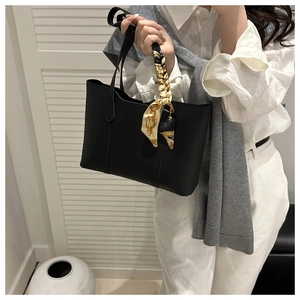Detail of black leather tote bag featuring a decorative vintage floral silk scarf handle