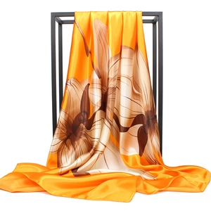 Detailed close-up of a 90cm satin silk scarf with orange floral print and smooth texture