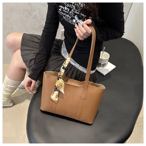 Brown tote bag with decorative silk scarf handle shown in a stylish lifestyle setting