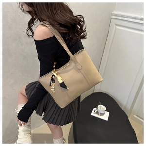 Sac cabas en cuir beige avec détail de foulard en soie porté par un mannequin chic
