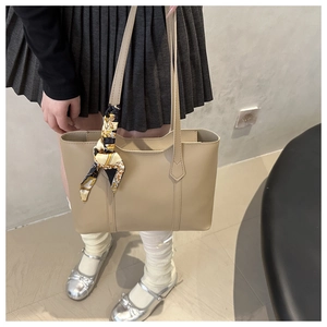 Close-up of beige leather tote bag featuring a vintage pattern silk scarf on handle